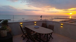 A rooftop terrace with a table and chairs, overlooking the sea at sunset. - The Red house 1930 - frontside seaview apartment (Lido di Ostia)