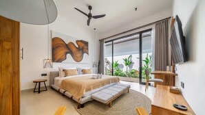 A modern bedroom with a bed, a desk, a chair, a ceiling fan, and a large window with curtains. - Julia Villa Bali (Gianyar)