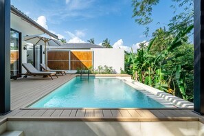 Una piscina al aire libre, sillones reclinables de piscina