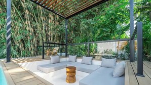A modern outdoor seating area with a pool, surrounded by lush greenery and bamboo. - Julia Villa Bali (Gianyar)