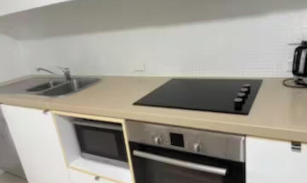 A kitchen with a sink, a stove, and a microwave.