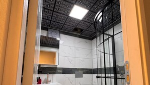 Un baño moderno con cabina de ducha de vidrio, inodoro blanco y suelo de mármol.