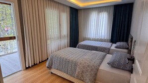 Un dormitorio moderno con dos camas, una puerta corrediza de vidrio y una lámpara en el techo.