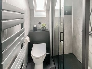A compact bathroom with a toilet, a small sink, a towel dispenser, and a potted plant. - 3 bedroom accommodation in Roag, near Dunvegan (Roag, near Dunvegan)