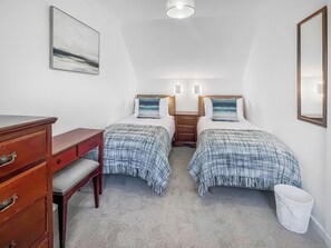 A bedroom with two beds, a dresser, a nightstand, a lamp, and a painting on the wall.