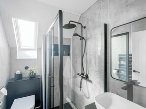 A modern bathroom with a glass shower enclosure, a white sink, and a mirror.