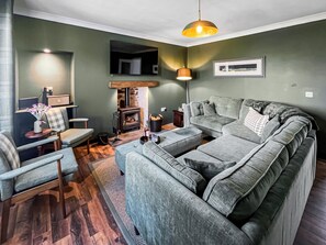 A living room with a sofa, armchairs, a fireplace, and a hanging light fixture.