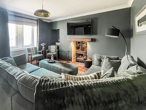 A modern living room with a sofa, armchairs, a coffee table, a fireplace, and a TV mounted on the wall. - 3 bedroom accommodation in Roag, near Dunvegan (Roag, near Dunvegan)