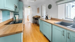 Een keuken met lichtblauwe kastjes, een houten aanrecht, een spoelbak en een eethoek met stoelen.
