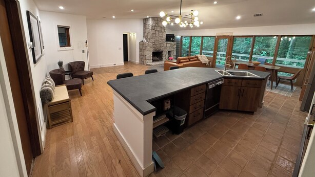 Una cocina amplia con chimenea de piedra, un comedor con ventana grande y una sala de estar con sofá y sillones.