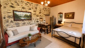 Una habitación acogedora con pared de piedra, un sofá, una mesa de comedor y una cama.