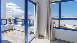 Ein Balkon mit blauen Geländern, Blick auf das Meer und einen klaren Himmel.