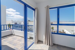Ein Balkon mit blauen Geländern, Blick auf das Meer und einen klaren Himmel.