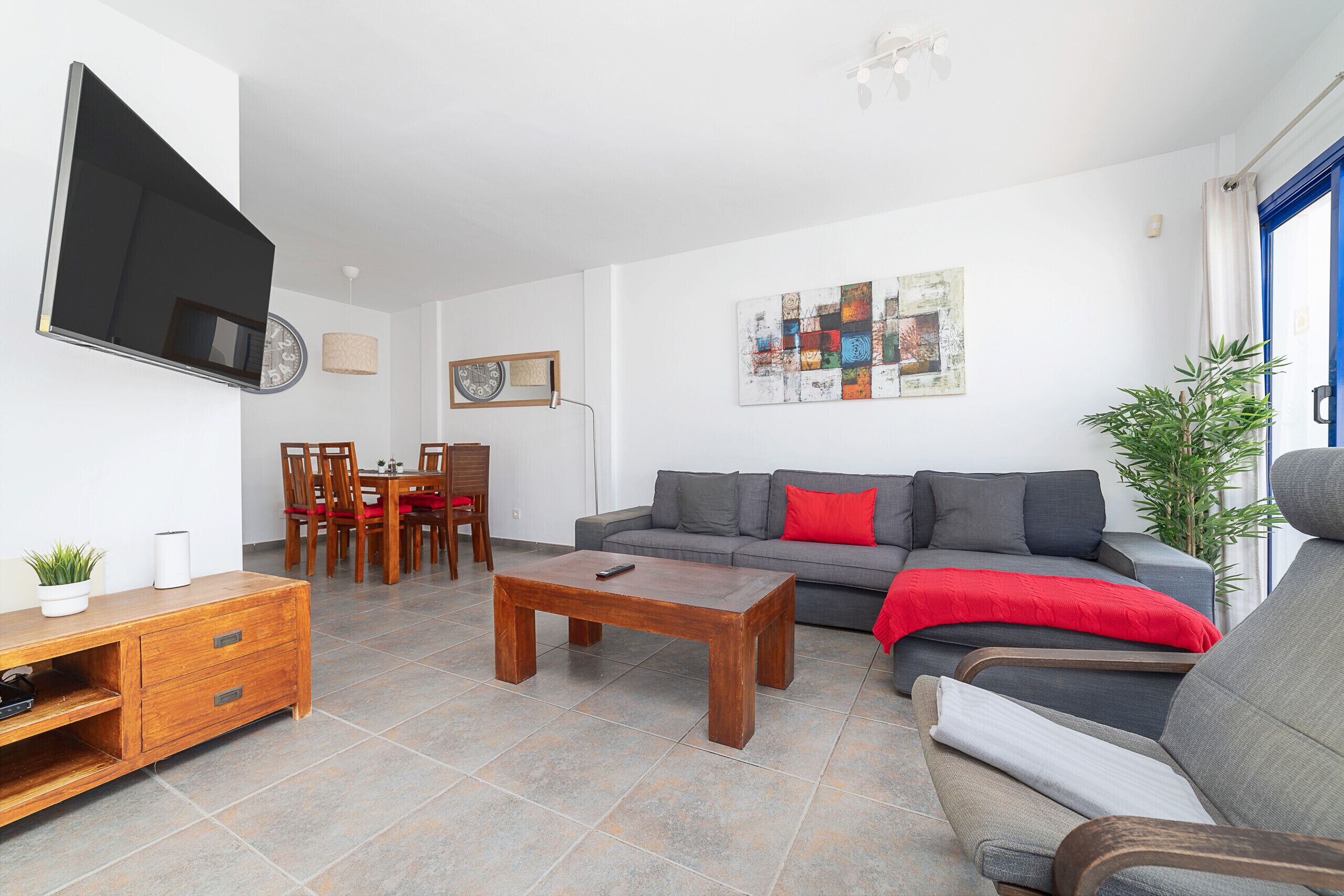 Una sala de estar con sofá, mesa de centro, televisor y un comedor con sillas y mesa.