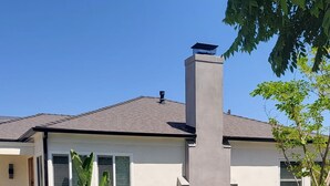 A modern house with a chimney, a well-maintained lawn, and a concrete pathway.