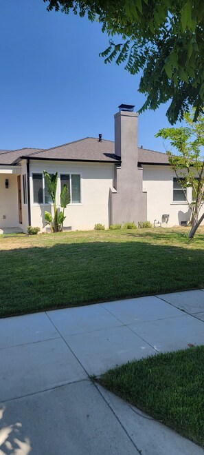 A modern house with a chimney, a well-maintained lawn, and a concrete pathway. - Cozy 2-bedroom house in perfect Burbank with AC (Burbank)
