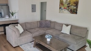 A living room with a sofa, coffee table, and a painting on the wall.