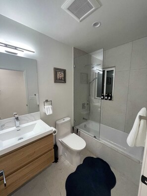 Un baño moderno con un espejo grande, un lavabo, un inodoro, una ducha y una bañera.