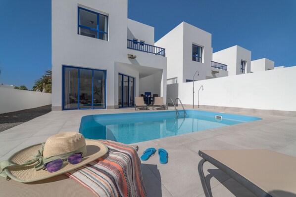 Ein modernes Gebäude mit Schwimmbad, Lounge-Bereich und Esstisch.