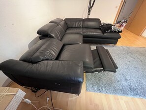 Ein modulares Sofa mit Liegefunktion, ein grauer Teppich und ein Holzboden.