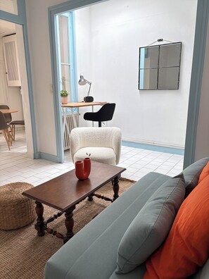 Ein modernes Wohnzimmer mit Sofa, Couchtisch, Sessel und Schreibtisch mit Lampe und Radio.
