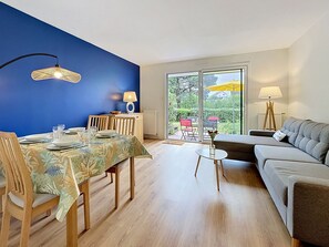 Ein Essbereich mit Tisch für vier Personen, einer Couch und Blick ins Freie.