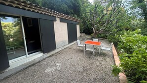 A building with a tiled roof, a gravel patio, and a table with chairs.