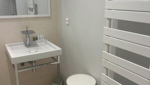 A bathroom with a white sink, mirror, and a toilet with a white lid.