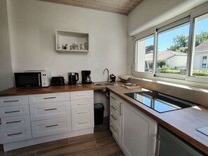 Een kleine keuken met een magnetron, koffiezetapparaat en spoelbak.