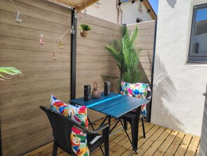 Een terras met een tafel en stoelen, een hanglamp en een bloempot.
