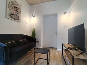 Un salon avec un canapé, une petite table, un téléviseur et une porte.
