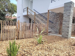 Un bâtiment moderne avec une clôture en bois, un escalier et un pilier en pierre.