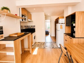 Eine moderne Küche mit Holzschränken, einer Mikrowelle, einer Waschmaschine und einem Kühlschrank.