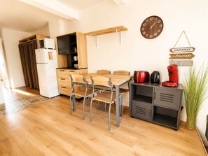 Une cuisine moderne avec une table à manger en bois, des chaises, une horloge et une machine à café.