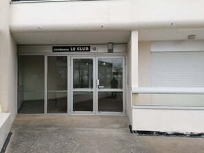LâentrĂ©e dâun immeuble, avec une plaque indiquant « rĂ©sidence LE CLUB 12 ».