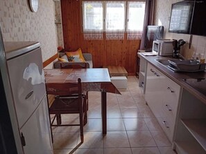 Una cocina compacta con una mesa de comedor, un refrigerador, un microondas y un lavamanos.