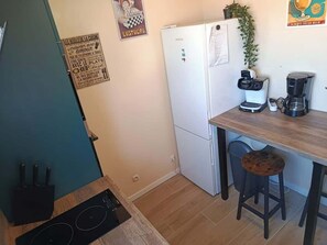A compact kitchen with a white refrigerator, a coffee maker, a sink, and a wooden countertop. - appartement cosy proche plage et commerces (Saint-Jean-de-Monts)