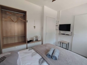 Ein Hotelzimmer mit einem Bett, einem Kleiderschrank, einem Fernseher und einem kleinen Tisch.