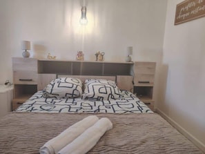 Un letto rifatto con cuscini decorati, una lampada da comodino e un piccolo oggetto decorativo sul tavolino.