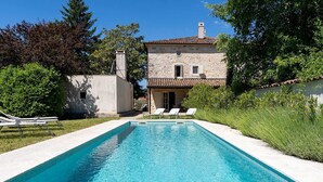 A rectangular swimming pool with a stone building in the background, a clear sky, and greenery around. - Villa Eva Rustica (100591-K1) - Zbandaj (Zbandaj)