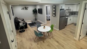Eine moderne Küche mit weißen Schränken, einem Kühlschrank und einem Essbereich mit rundem Tisch und Stühlen.