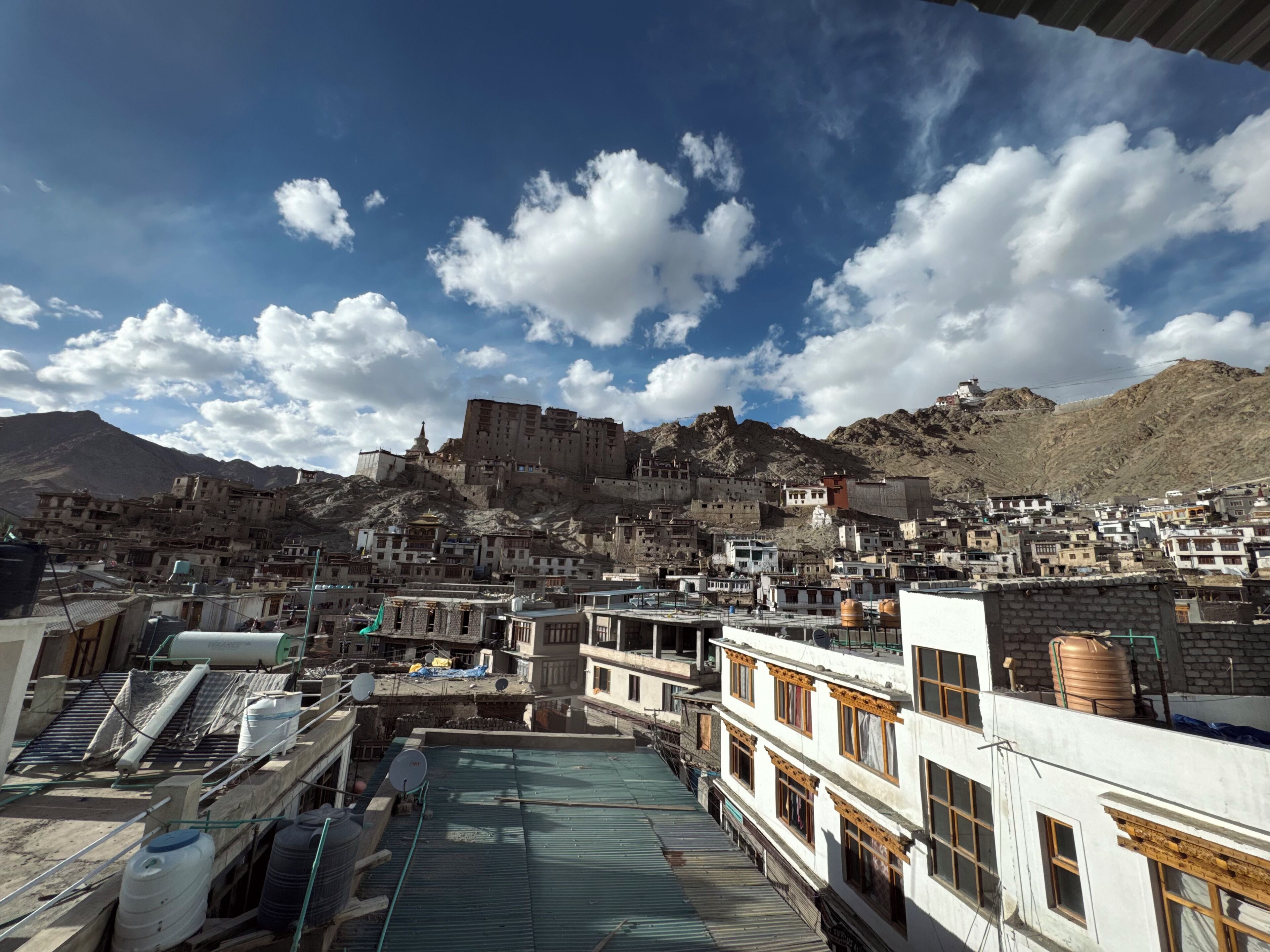 A mountainous town with traditional buildings, a prominent fortress-like structure on a hill, and a clear sky.