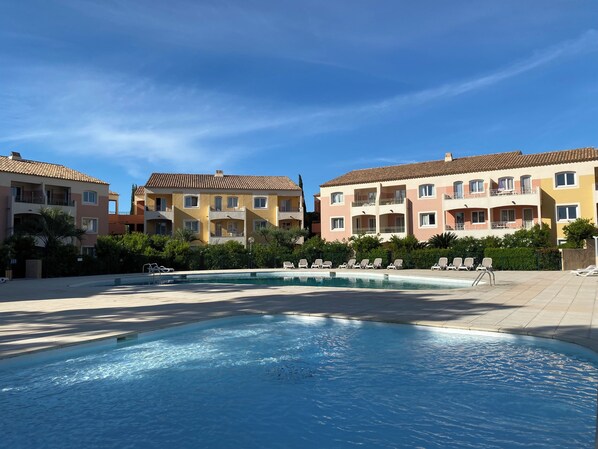 Un hotel amb piscina, diversos balcons i cel blau.
