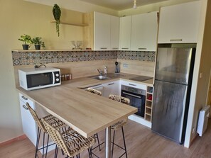 Une cuisine compacte Ă©quipĂ©e dâun four Ă micro-ondes, dâun Ă©vier, dâune cuisiniĂšre et dâun rĂ©frigĂ©rateur.