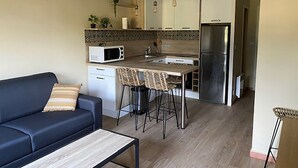 Eine kompakte Küche mit Mikrowelle, Kühlschrank und Barhocker.