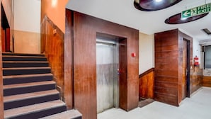 Una escalera que conduce a un ascensor, un letrero de salida de incendios y una puerta con un extintor.