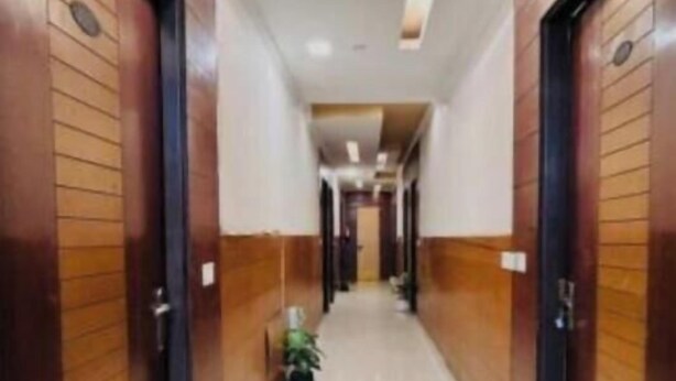 Un pasillo de hotel con puertas de madera, suelo de baldosas e iluminación empotrada.