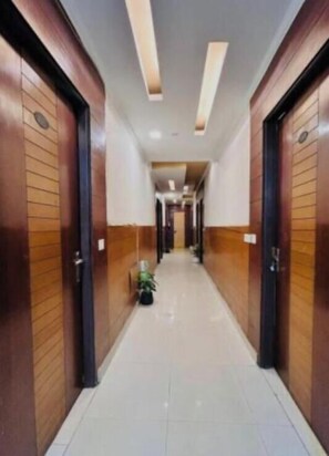 Un pasillo de hotel con puertas de madera, suelo de baldosas e iluminación empotrada.