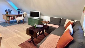 Un soggiorno in stile loft con un divano, una televisione, una libreria e un tavolino.