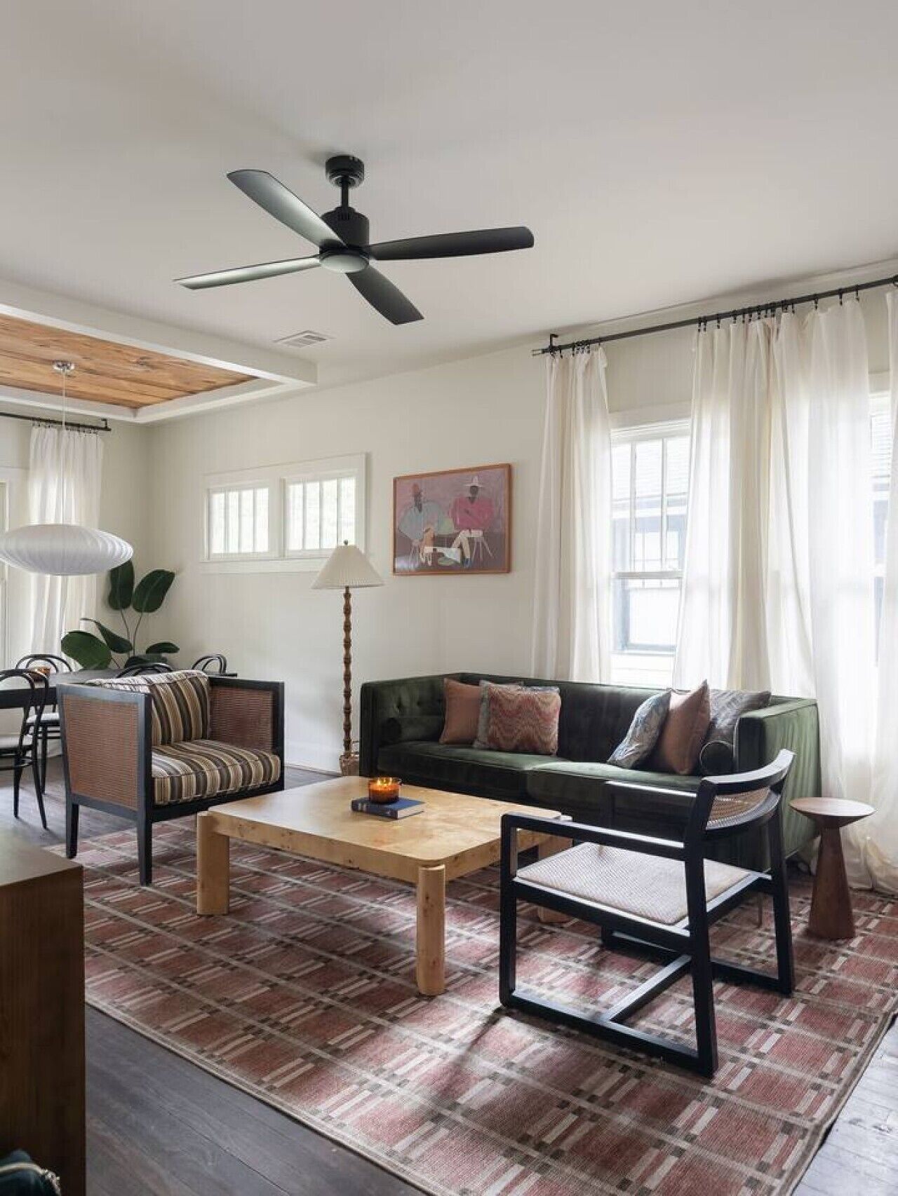 A living room with a ceiling fan, a sofa, a coffee table, and a dining area with chairs.